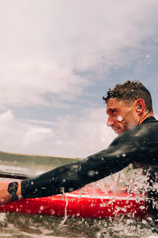 Un hombre sobre una tabla de paddle surf en el agua con un Apple Watch Series 10.